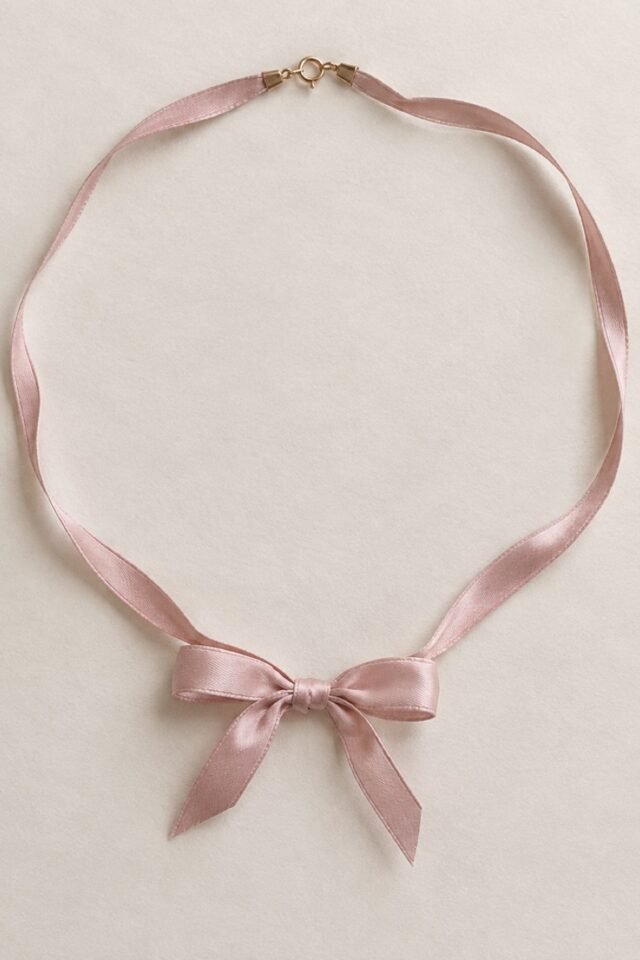 Colette Bow Necklace in blush pink, laid flat.
